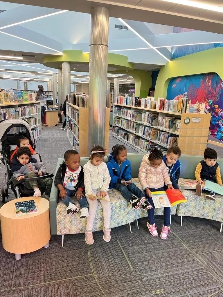 Children reading books in a library seating area